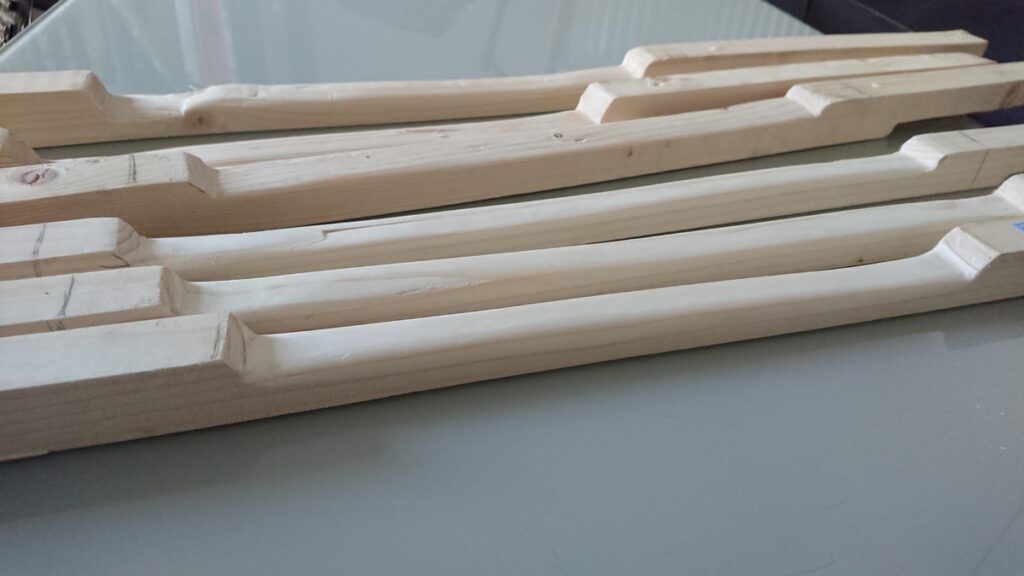 Six tasseaux de sapins, sculptés en forme de manche de guitare.