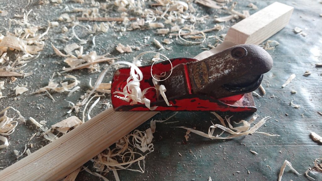 Un rabot posé sur un tasseau de sapin.