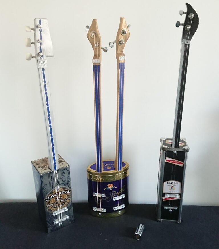 Trois Whisky Box Guitars, de diverses couleurs.