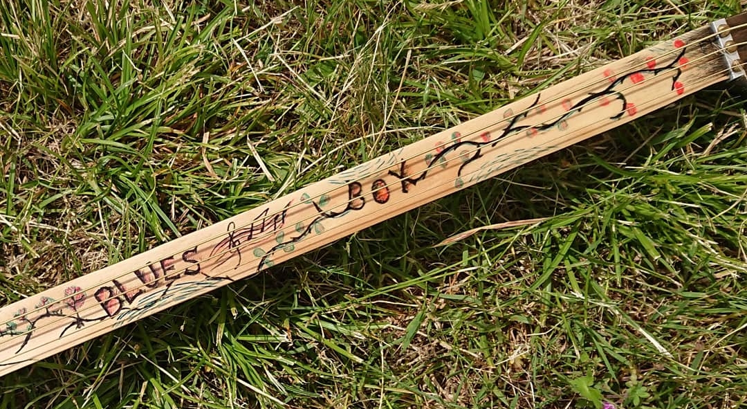 La manche d'un cordophone présentant des dessins au stylo.